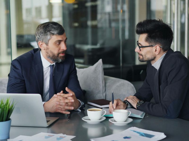 due uomini parlano in ufficio a simbolo della consulenza finanziaria aziendale personalizzata