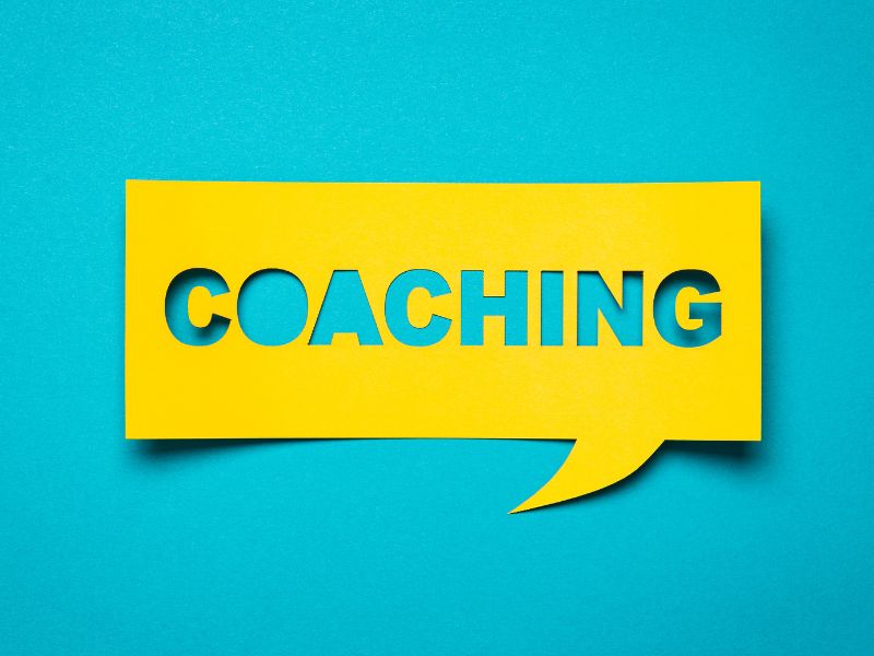 scritta gialla ritagliata coaching su sfondo azzurro