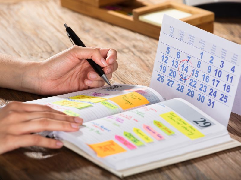 donna scrive su un'agenda con dei post it colorati