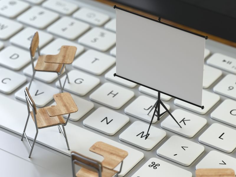 sedie e lavagna su computer a indicare la formazione del personale online