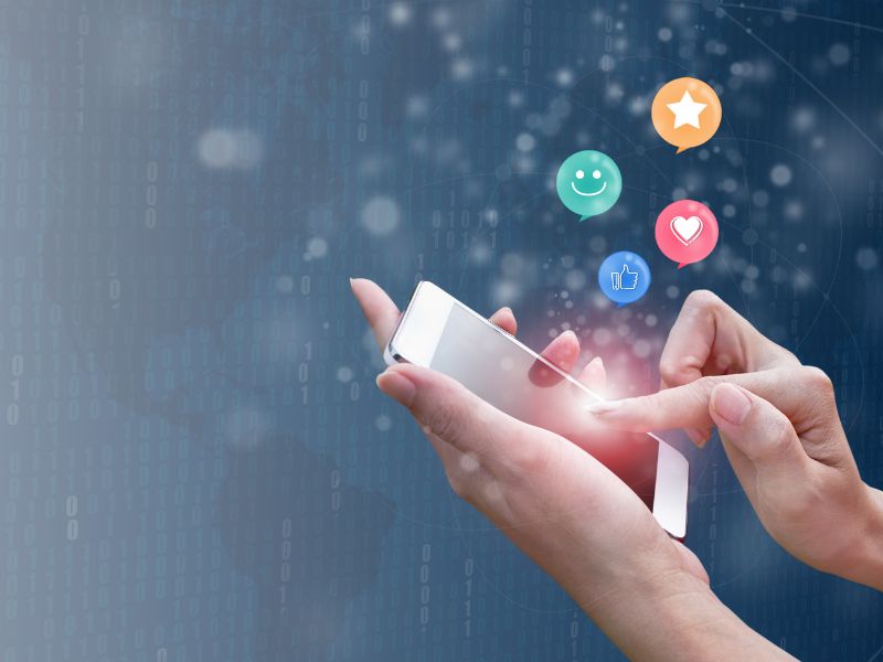 mano su smartphone con emoji