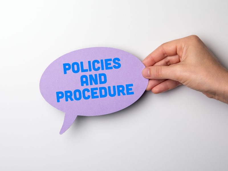mano tiene un post it con scritto policies and procedures